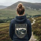 Person wearing a hoodie with 'Contae Chill Mhantain Wicklow' design in a scenic landscape.