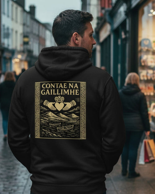 Man wearing a black hoodie with a gold design and text on a city street.