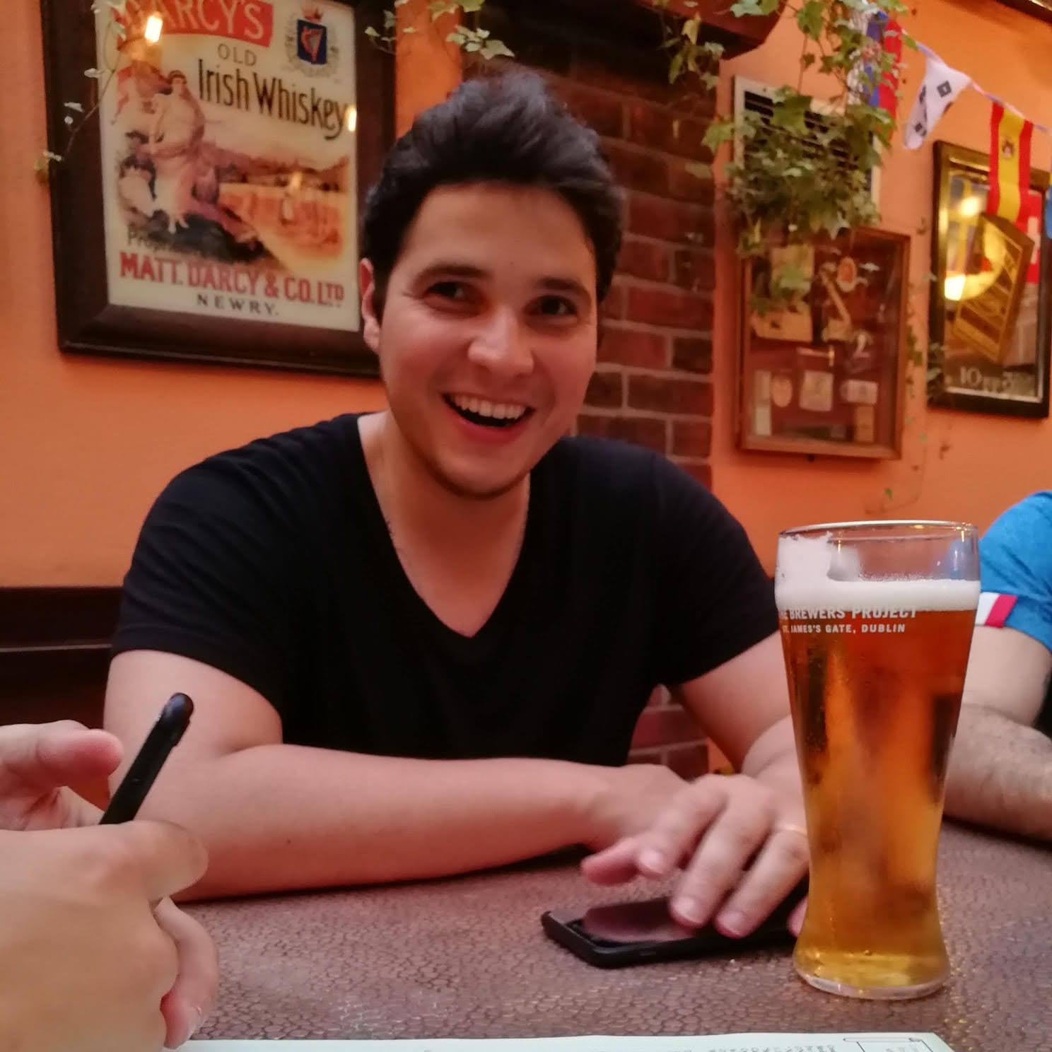 Person sitting at a bar with a beer and menu, smiling.