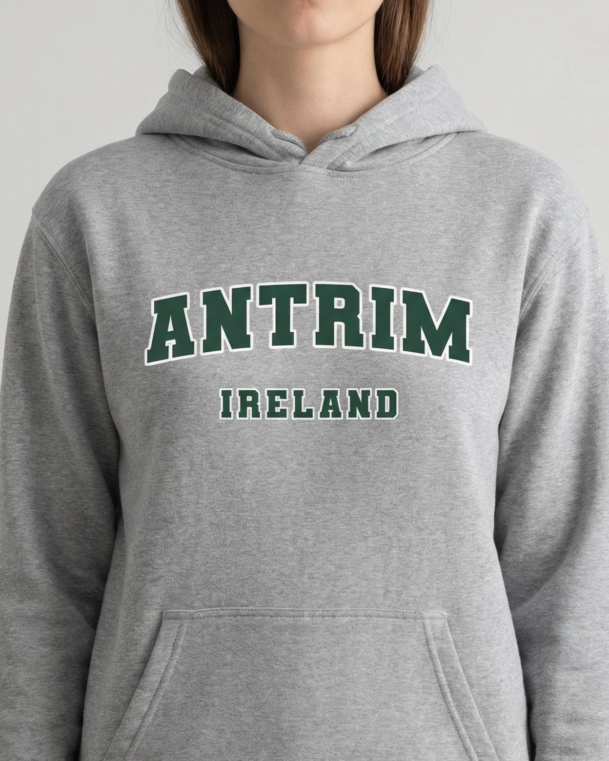 Gray hoodie with 'Antrim Ireland' text worn by a person on a light gray background