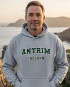 Man in grey Antrim Ireland hoodie outdoors by scenic Irish coastline